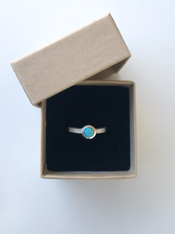 Round created blue opal ring in ring box